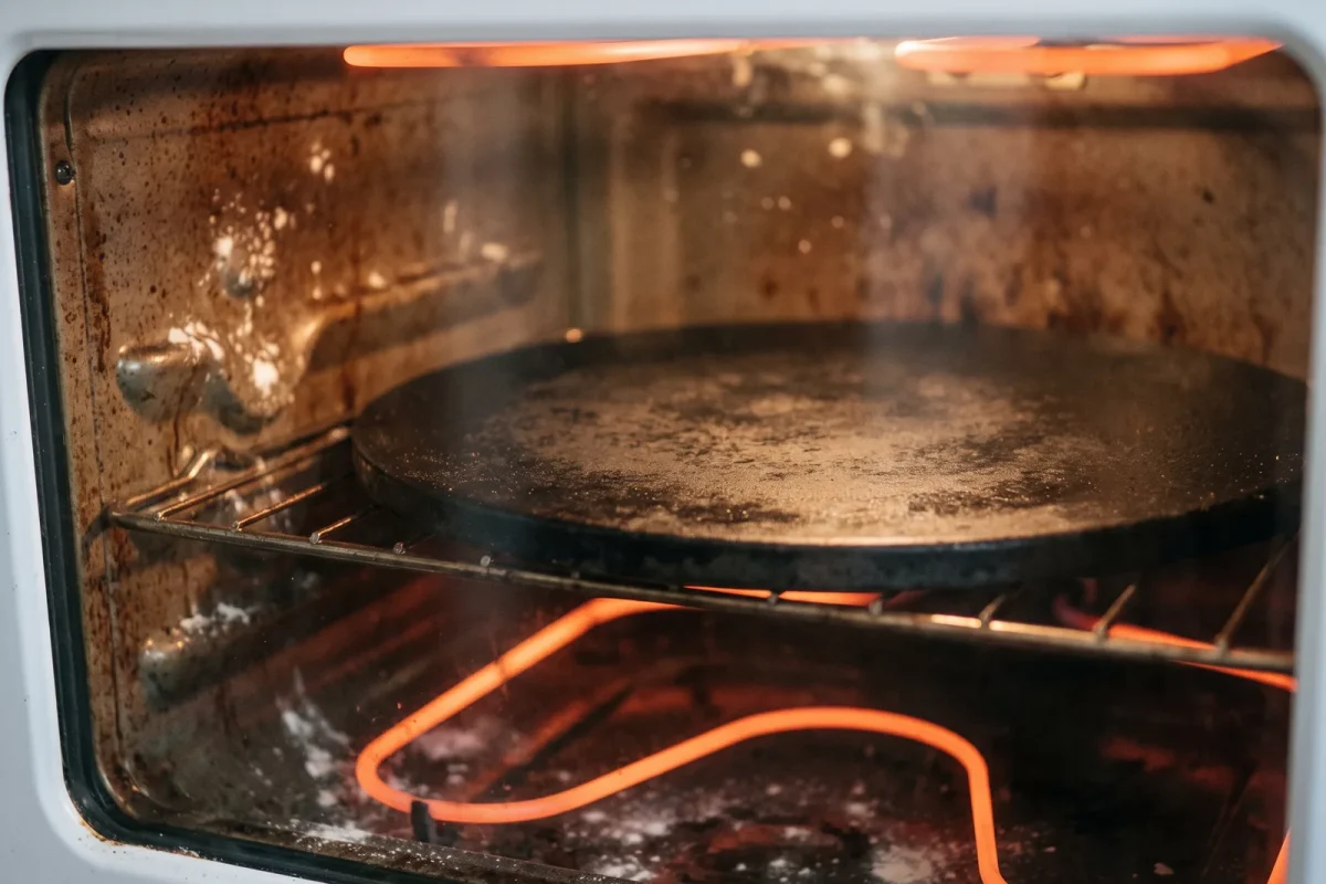 Ett tjockt svart pizzastål som förvärms glödvarmt inne i en hemmaugn
