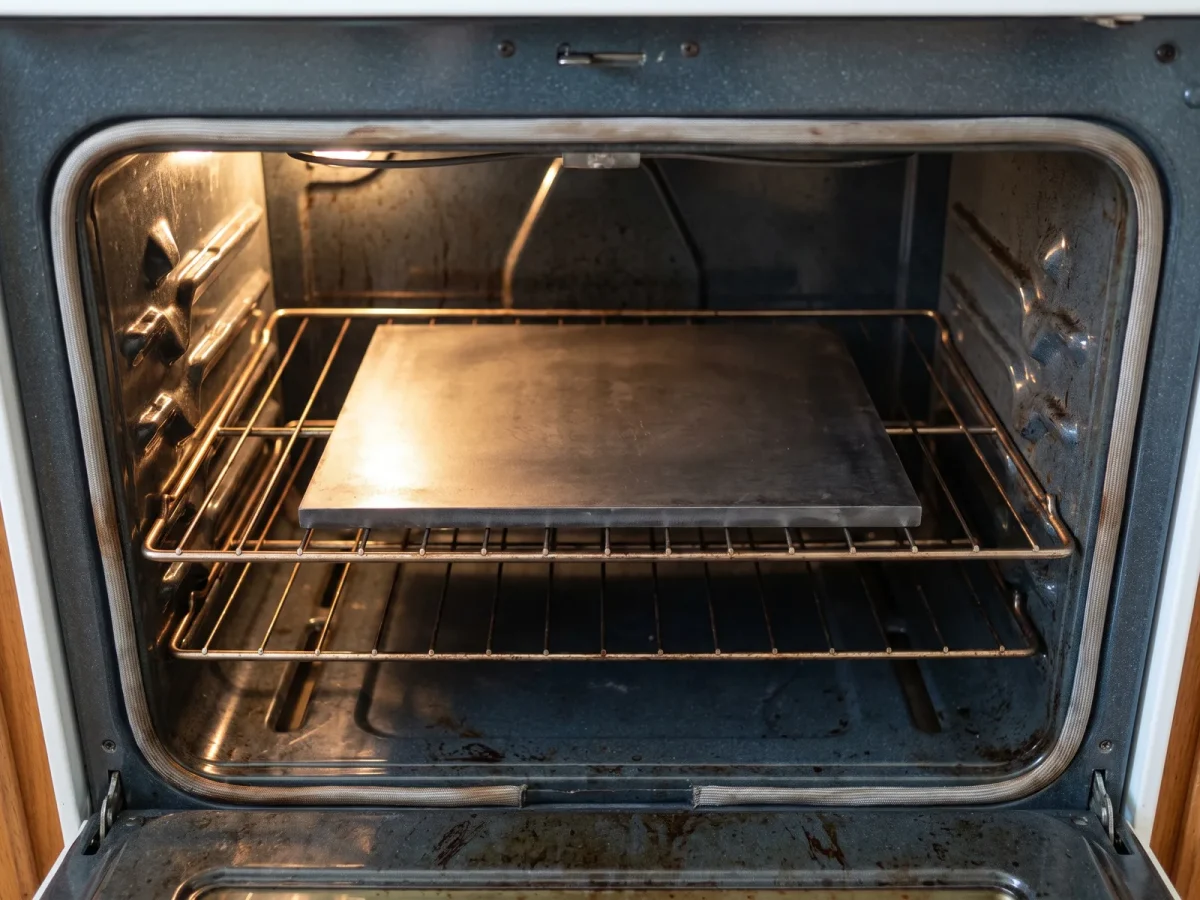 Ett tjockt stålpizzastål mäts upp mot väggarna inne i en hemmaugn
